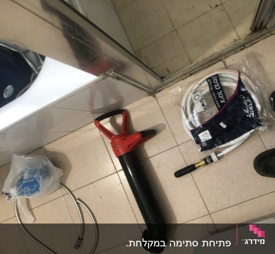 כלי עבודה של אינסטלטור על רצפה, כולל צינור ואביזרים